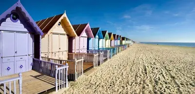 a row of colorful beach huts on the beach at Digby House flat 1 in West Mersea