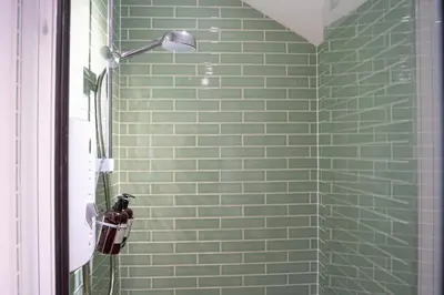 a green tiled shower with a light fixture in a bathroom at The Cotswold Luxe Cottage in Framlingham