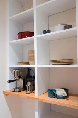 a kitchen shelf with cups and plates and a coffee maker at The Cotswold Luxe Cottage in Framlingham