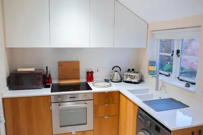 a kitchen with white cabinets and a stove top oven at The Cotswold Luxe Cottage in Framlingham