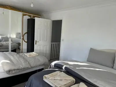 a bedroom with two beds and a closet with towels at Chartsworth 4 Bedrooms Spacious House in Harold Wood