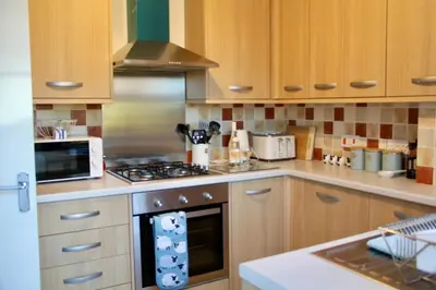a kitchen with wooden cabinets and a stove top oven at Seaside Luxury Cottage Aldeburgh in Aldeburgh