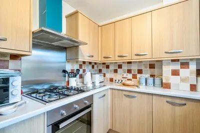 a kitchen with wooden cabinets and a stove top oven at Seaside Luxury Cottage Aldeburgh in Aldeburgh