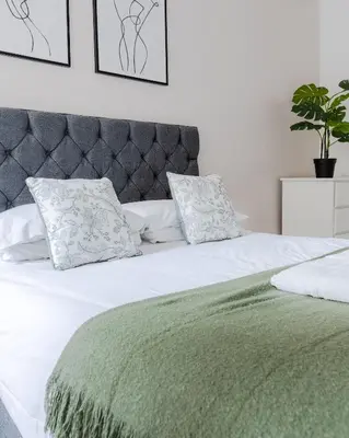 a white bed with a green blanket and pillows at The Regency | Seafront Lux Apartments! in Southend-on-Sea