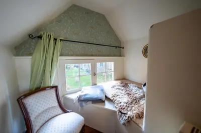 a small room with a window with a bed and a chair at The Old Rectory Framlingham in Framlingham