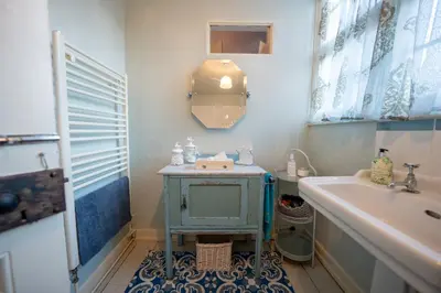 a bathroom with a blue sink and a tub at The Old Rectory Framlingham in Framlingham