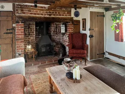 a living room with a table and a brick fireplace at Hill House in Colchester