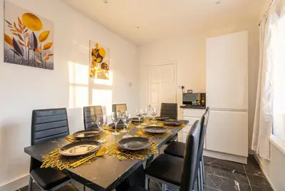 a dining room with a table and chairs and a kitchen at Spacious 3-Bed Home for 8 | Free Parking & Garden in Havering atte Bower