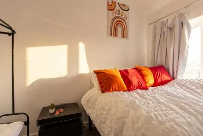 a bedroom with a bed with colorful pillows on it at Spacious 3-Bed Home for 8 | Free Parking & Garden in Havering atte Bower