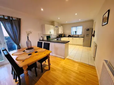 a kitchen and dining room with a wooden table at Modern home close to amenities and transport links in Wymondham