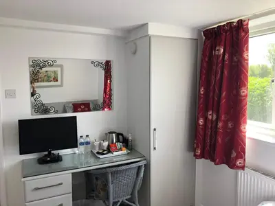 a room with a desk with a television and a window at Acreland Green in Pleshey