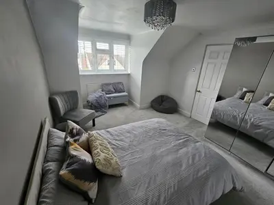 a bedroom with a bed and a couch and a mirror at Luv home with pool and cinema room