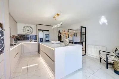 a kitchen with white cabinets and a counter top at Luv home with pool and cinema room