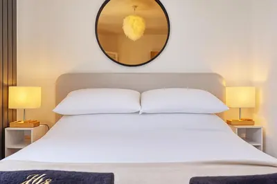 a bedroom with a white bed with a mirror above it at Luxury Apartment- Beach 10mins in Thorpe Bay
