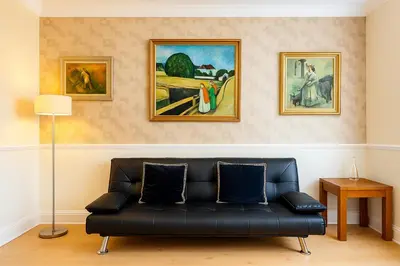 a black couch in a living room with paintings at 1 Bed Service Accommodation- contractor ready in Southend-on-Sea