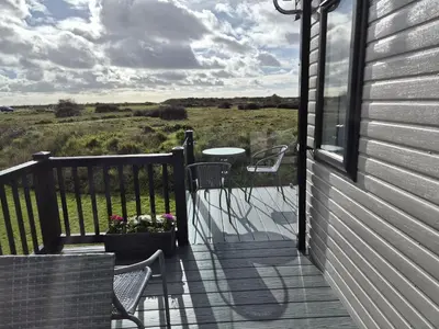 a balcony with a table and chairs on a house at Modern 6 Berth Caravan With Decking At Suffolk Sands Ref 45004F in Felixstowe
