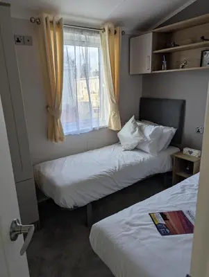 two beds in a small room with a window at Modern 6 Berth Caravan With Decking At Suffolk Sands Ref 45004F in Felixstowe