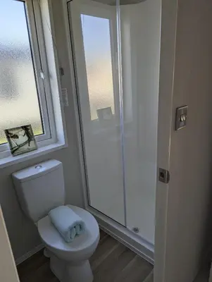 a bathroom with a white toilet and a window at Modern 6 Berth Caravan With Decking At Suffolk Sands Ref 45004F in Felixstowe