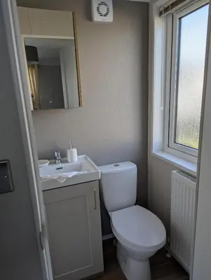 a bathroom with a toilet and a sink and a mirror at Modern 6 Berth Caravan With Decking At Suffolk Sands Ref 45004F in Felixstowe