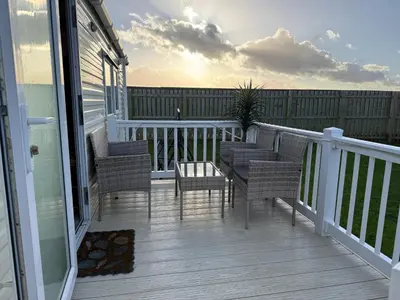 a porch with chairs and a table on a balcony at Coastal Beachfront Caravan in Brightlingsea