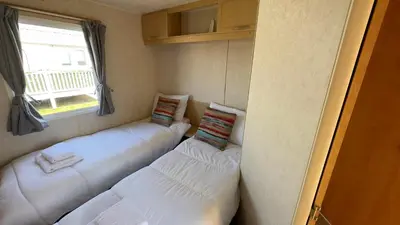 a room with three white pillows and a window at Suntrail House in Great Clacton