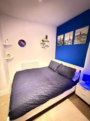 a bedroom with a bed with a blue wall at The Coral Stay By Cambridge Central Station in Cambridge