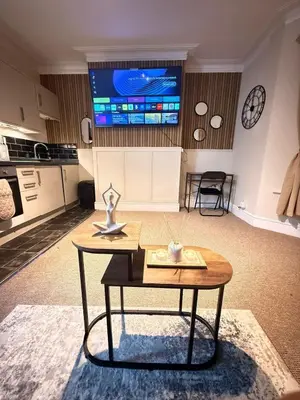 a living room with a table and a tv on the wall at The Coral Stay By Cambridge Central Station in Cambridge