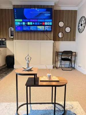 a room with a table and a tv on the wall at The Coral Stay By Cambridge Central Station in Cambridge