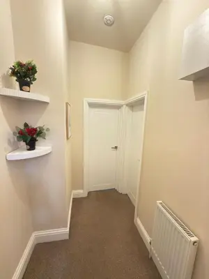 a hallway with a white door and flowers on shelves at The Modern Nest By Cambridge Central Station in Cambridge