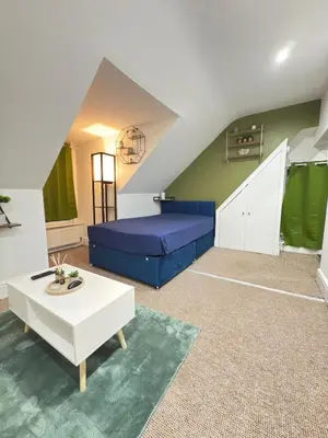 a living room with a blue bed and a table at The Traveller's Nest by Cambridge Central Station in Cambridge