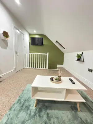 a living room with a white table and a tv at The Traveller's Nest by Cambridge Central Station in Cambridge