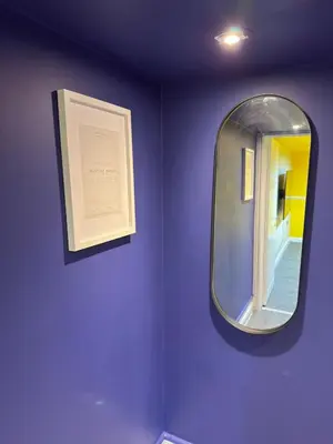 a mirror on a purple wall with a picture at The Squid Escape By Cambridge Central Station in Cambridge