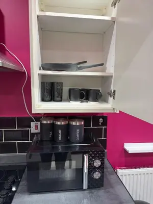 a kitchen with a black microwave in a pink wall at The Squid Escape By Cambridge Central Station in Cambridge