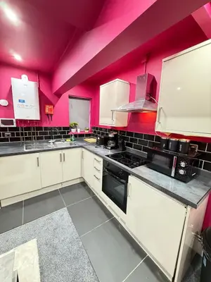 a kitchen with white cabinets and pink walls at The Squid Escape By Cambridge Central Station in Cambridge