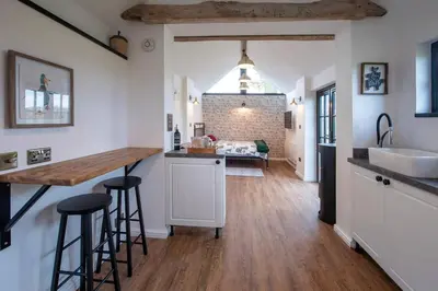 a kitchen with a counter and stools and a sink at The Acorn - Roudham Norwich in Norwich
