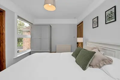 a white bedroom with a large bed and a window at 10 Mustow St - Charming 3 bed home next to the Abbey Gardens in Bury St Edmunds in Bury Saint Edmunds