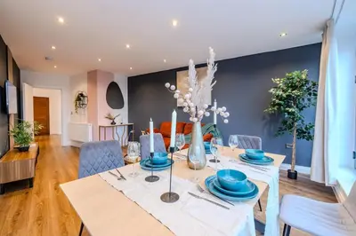 a dining room with a table and blue chairs at Lux 2 Bedroom Flt at Brentwood in Brentwood