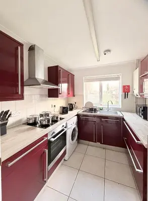 a kitchen with red cabinets and a sink and a dishwasher at Stylish 3BR Cambridge Bungalow, Near Science Park in Cambridge