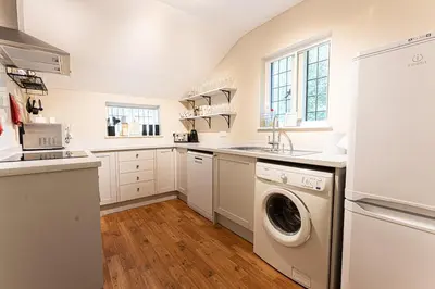 a white kitchen with a washer and dryer in it at Idyllic, Private and Picturesque Cottage in Newmarket