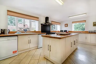 a large kitchen with white cabinets and wooden floors at 9 Bed in Three Holes oc-l31856 in Upwell