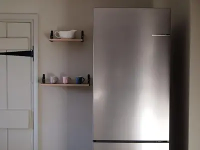 a stainless steel refrigerator in a kitchen with shelves at Beautiful Four Bedroom Cottage in Little Glemham, Suffolk in Little Glenham