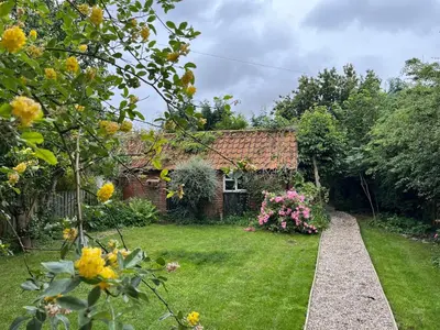 a garden with a brick house with flowers at Beautiful Four Bedroom Cottage in Little Glemham, Suffolk in Little Glenham