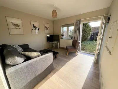a living room with a couch and a television at Beautiful Four Bedroom Cottage in Little Glemham, Suffolk in Little Glenham