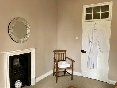 a robe hanging on a door with a chair and a mirror at Grange Farm in Thetford