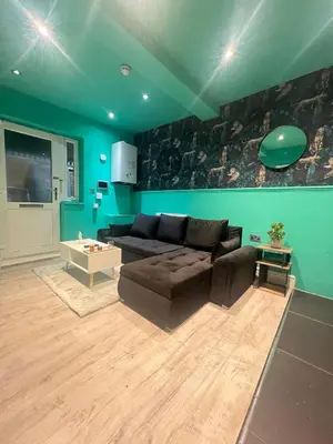 a living room with a brown couch and a green wall at The Emerald Aura Stay By Cambridge Central Station in Cambridge