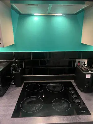 a stove top in a kitchen with a green wall at The Emerald Aura Stay By Cambridge Central Station in Cambridge