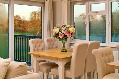 a dining room with a table and chairs and a vase of flowers at Finest Retreats - Heron Luxury Lodge