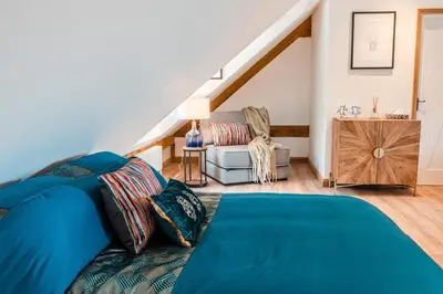 a bedroom with a blue bed and a chair at Hare View, part of The Garden House in Kenninghall
