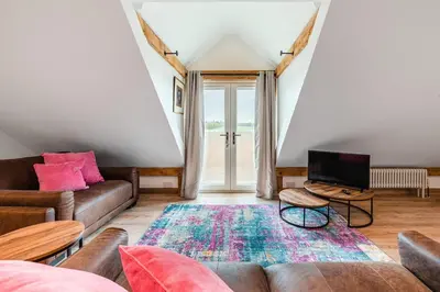a living room with a couch and a tv at Hare View, part of The Garden House in Kenninghall