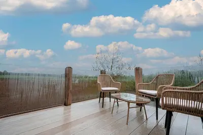 a balcony with chairs and a table on a wooden floor at Hare View, part of The Garden House in Kenninghall
